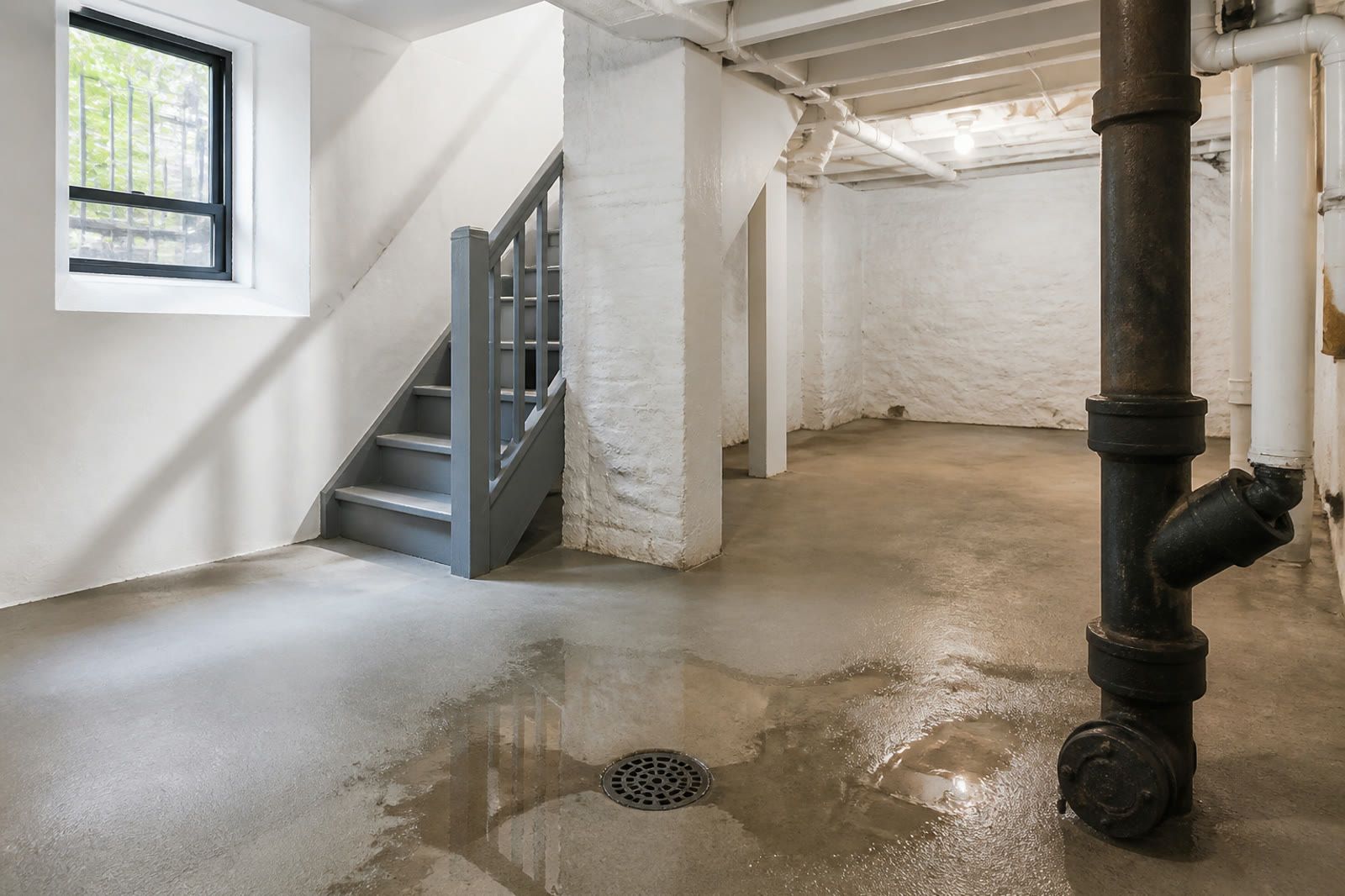 Well-lit cellar floor drain with a controlled sheen of rainwater nearby